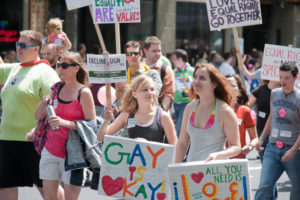 An image of Seattle's Pride Festival. People are holding numerous signs, including one that reads, "Gay is okay."