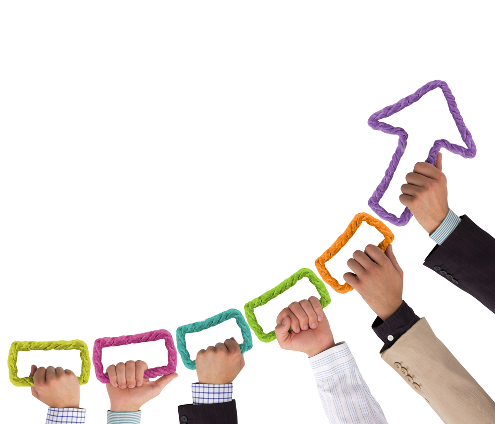 An image of people holding a rainbow-colored arrow that is pointing upward.