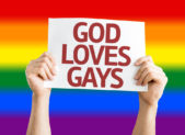 Reframing Biblical Views on the LGBTQ+ Community A person holding up a sign that reads, "God loves gays." There is a rainbow in the background.