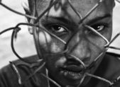 How Many of These Covert Acts of Racism Have You Experienced? A close-up of an African American behind a fence.