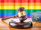 Same-Sex Couple Given Equal Parental Rights in Historic Civil Rights Case A gavel with a rainbow flag in the background.