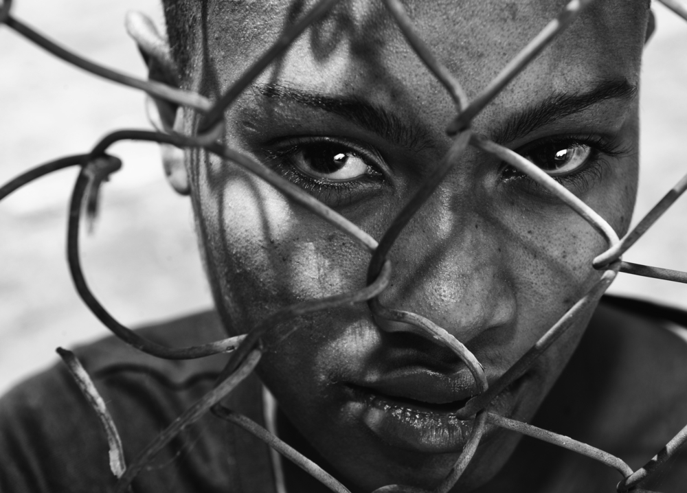 A close-up of an African American behind a fence.
