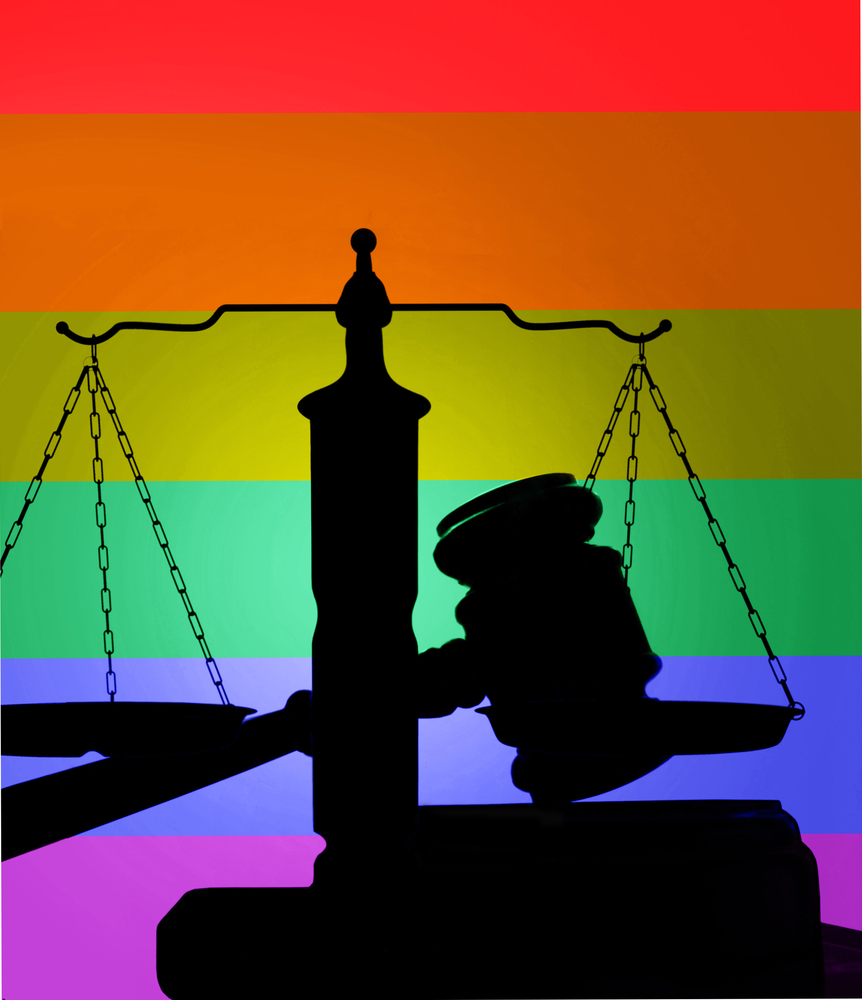 The silhouette of a gavel and the scales of justice juxtaposed against a rainbow background.